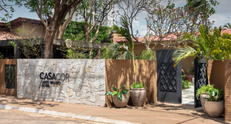 Fachada de entrada da CASACOR Mato Grosso do Sul 2025 em Campo Grande, com paisagismo tropical e letreiro da mostra em destaque.