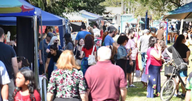 Vista colorida da Feira Borogodó na Praça do Coophafé, com expositores, famílias e decoração artesanal em clima festivo de economia criativa