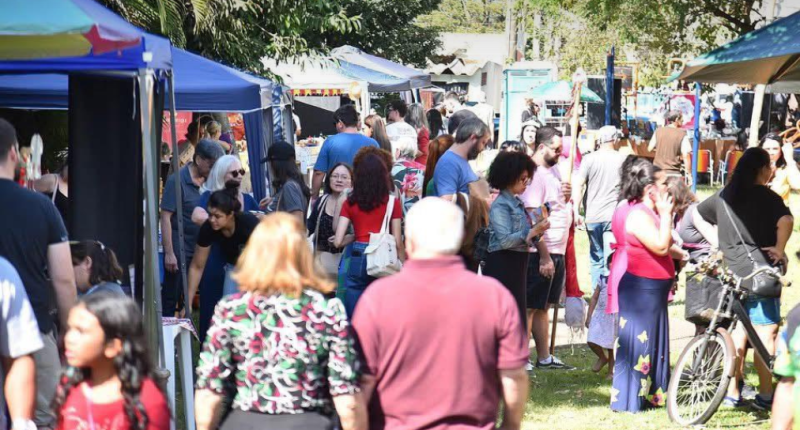 Vista colorida da Feira Borogodó na Praça do Coophafé, com expositores, famílias e decoração artesanal em clima festivo de economia criativa
