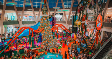 Corredores iluminados do Shopping Bosque dos Ipês com decoração de Natal e pessoas fazendo compras