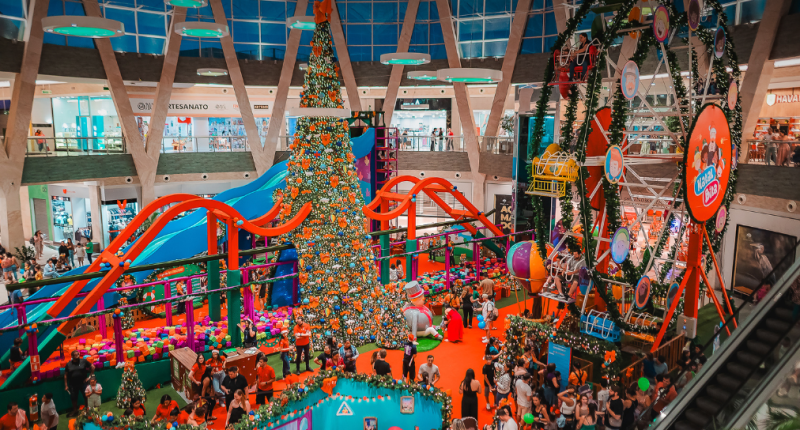 Corredores iluminados do Shopping Bosque dos Ipês com decoração de Natal e pessoas fazendo compras