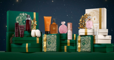 Embalagens de Natal do Boticário em tons de verde e dourado, com kits sofisticados dispostos em cenário iluminado, transmitindo elegância e clima festivo