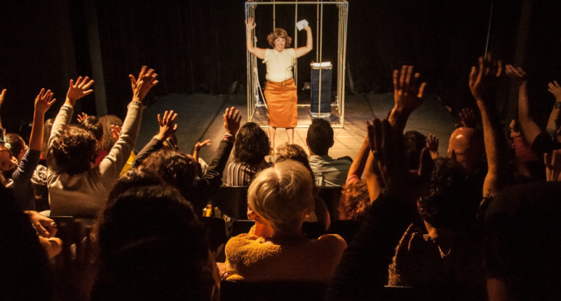 Atriz Vanderleia Will em cena como a palhaça de Desajustada, iluminada no palco, expressando emoção e humor em movimento físico poético.