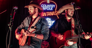 Renato Pacheco e Jonavo no palco em clima intimista, sob luz quente, tocando violas diante do público no Sunset Growler.