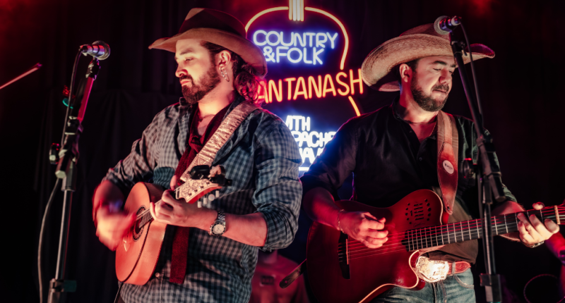 Renato Pacheco e Jonavo no palco em clima intimista, sob luz quente, tocando violas diante do público no Sunset Growler.