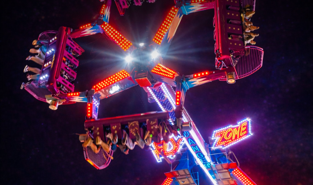 Brinquedos radicais iluminados no Vitinho Park durante a noite no Bosque dos Ipês