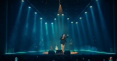 Imagem de Whindersson Nunes no palco, sob luzes intensas, expressando humor, emoção e a energia da turnê “Isso Definitivamente Não é um Culto”.