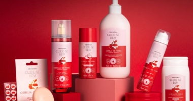 Produtos de cuidados corporais com embalagem em tons de cereja dispostos sobre fundo suave, transmitindo sensação de acolhimento e autocuidado