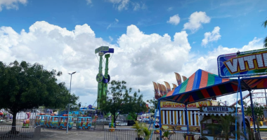 Parque de diversões colorido com roda gigante e brinquedos iluminados ao entardecer, com famílias se divertindo.
