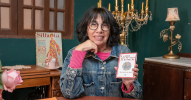 Escritora lendo poesia em café cultural durante encontro literário em Campo Grande