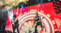 Palco de grande show de rock iluminado com multidão durante apresentação do Guns N’ Roses