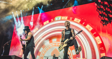 Palco de grande show de rock iluminado com multidão durante apresentação do Guns N’ Roses