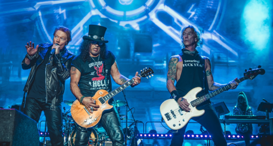 Palco iluminado com público em show do Guns N’ Roses durante apresentação de rock internacional