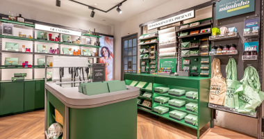 Loja do O Boticário iluminada em shopping com consumidores testando perfumes e produtos de beleza nas prateleiras