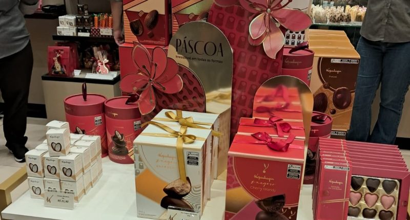 Vitrines de Páscoa com ovos de chocolate e decoração temática em shopping de Campo Grande com famílias circulando
