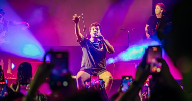 Cantor Chico Chico no palco com público participando em coro durante show noturno em Campo Grande