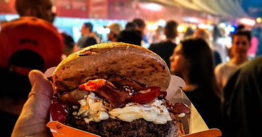 público e hamburguer reunido em festival gastronômico com hambúrgueres artesanais sendo preparados em chapas ao ar livre