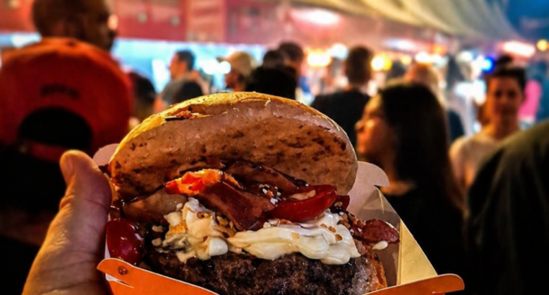 público e hamburguer reunido em festival gastronômico com hambúrgueres artesanais sendo preparados em chapas ao ar livre