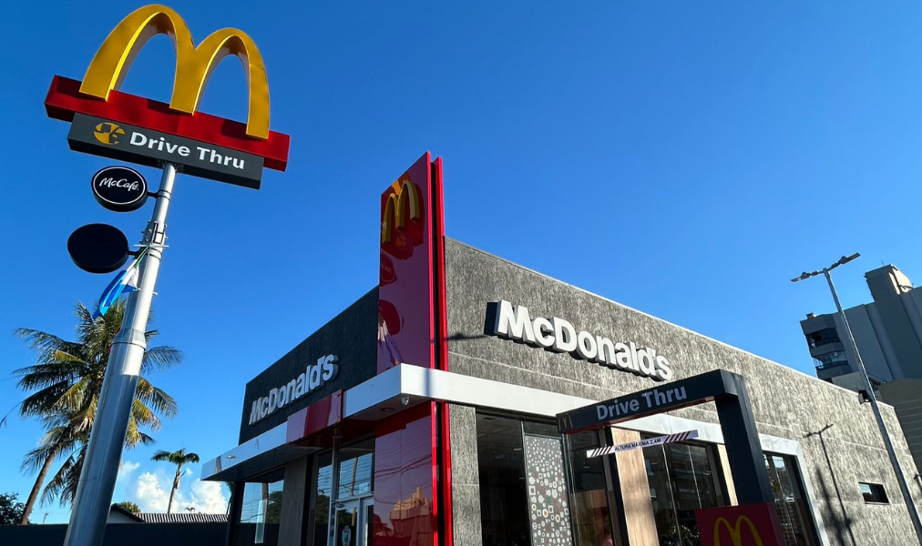 fachada moderna do McDonald’s com drive-thru e iluminação noturna em cidade do interior