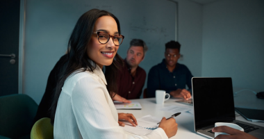Jornalista escrevendo reportagem em computador com logotipo do Prêmio Sebrae de Jornalismo ao fundo