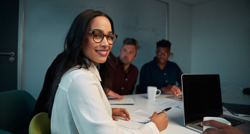 Jornalista escrevendo reportagem em computador com logotipo do Prêmio Sebrae de Jornalismo ao fundo