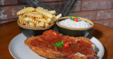 prato de parmegiana servido com arroz branco e batatas fritas, com molho de tomate e queijo derretido em destaque