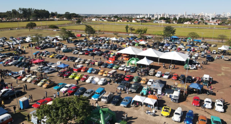 Carros antigos expostos durante encontro automotivo com público reunido em Campo Grande ao entardecer.