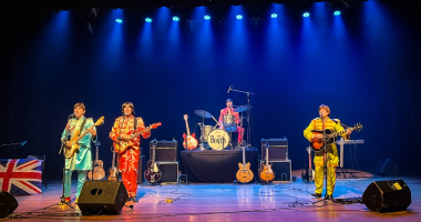 banda tributo Beatles em palco com figurinos clássicos e iluminação de show ao vivo
