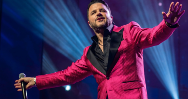 Maurício Manieri canta no palco durante apresentação da turnê “Classics – Inesquecível Tour”, cercado por iluminação intimista e clima nostálgico