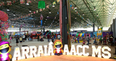 Público circulando entre barracas de comidas típicas durante o Arraiá da AACC/MS, em Campo Grande, em uma grande festa junina solidária.