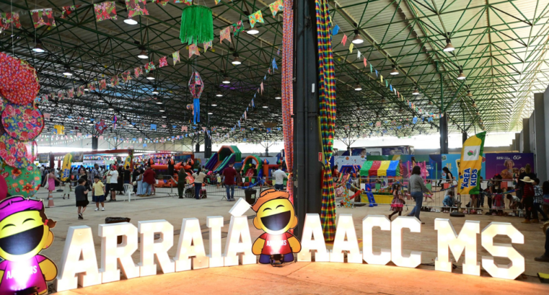 Público circulando entre barracas de comidas típicas durante o Arraiá da AACC/MS, em Campo Grande, em uma grande festa junina solidária.