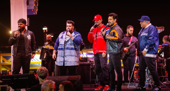 Artistas do projeto Cê Tá Doido durante show sertanejo com palco 360 graus.