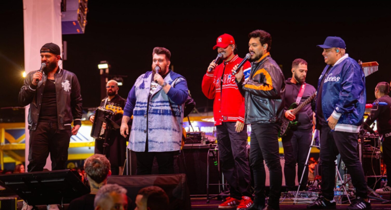 Artistas do projeto Cê Tá Doido durante show sertanejo com palco 360 graus.