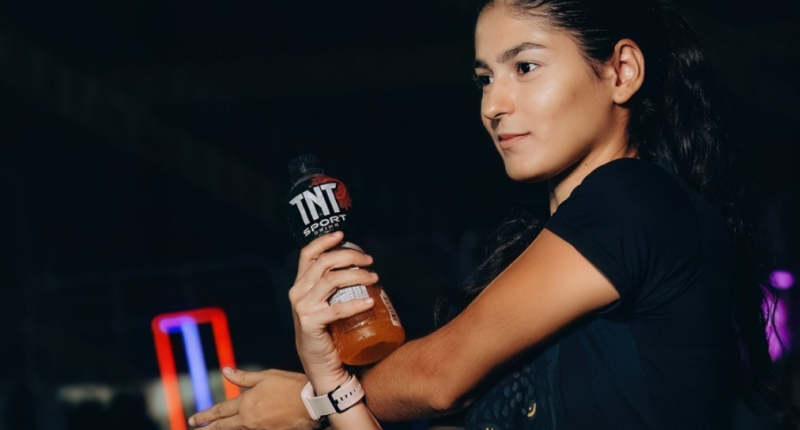 Corredores participam de prova de rua enquanto recebem hidratação em área de ativação da TNT Sport Drink durante evento esportivo