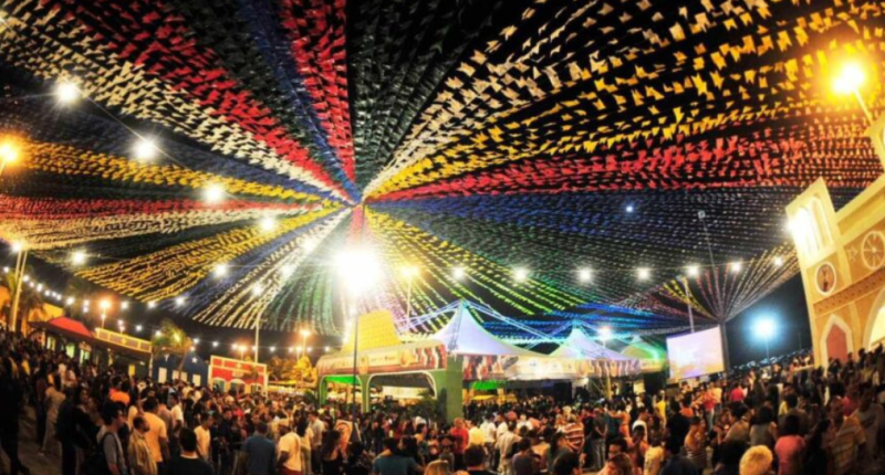 Público reunido em festa junina comunitária com barracas típicas, decoração colorida e clima de confraternização no Bairro União.