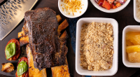 Costela bovina defumada da Fumatta servida com acompanhamentos artesanais, evidenciando a técnica de longa cocção e a gastronomia autoral desenvolvida em Campo Grande