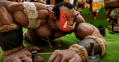 Escultura gigante de um orc em cenário temático montado nos corredores do Shopping Bosque dos Ipês durante exposição gratuita.