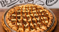 pizza doce Banana Real com banana, chocolate branco, creme especial e canela servidas sobre mesa de madeira