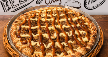 pizza doce Banana Real com banana, chocolate branco, creme especial e canela servidas sobre mesa de madeira