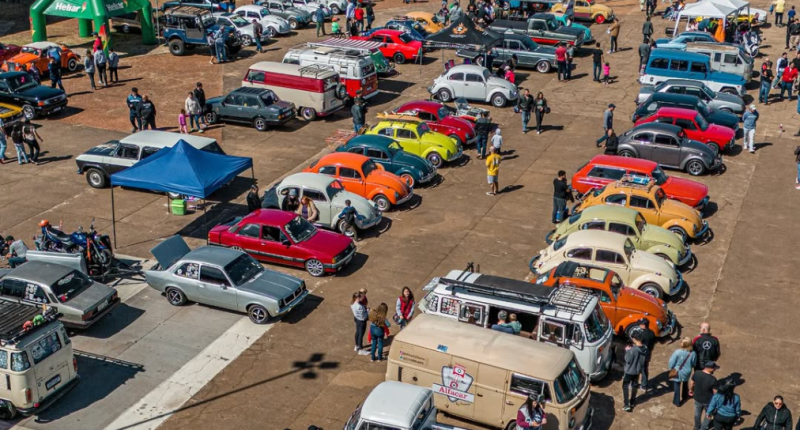 Veículos antigos expostos durante encontro automobilístico em Campo Grande com visitantes observando modelos clássicos restaurados.