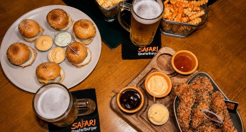 Mesa com chopp Brahma, mini burger e porções do happy hour do Safari Burger em Campo Grande.