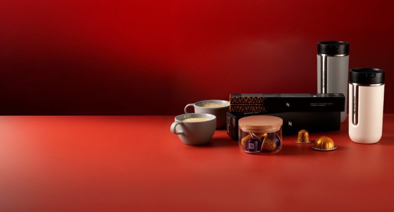 Máquina Nespresso prepara café ao lado de xícaras e cápsulas durante campanha de Dia dos Pais.