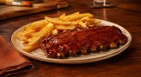 Duas porções de Junior Ribs servidas com acompanhamentos em uma mesa do Outback