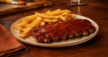 Duas porções de Junior Ribs servidas com acompanhamentos em uma mesa do Outback
