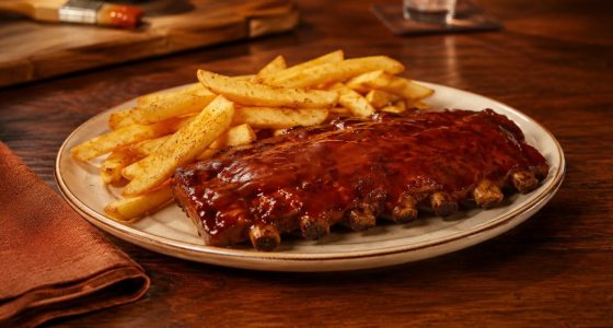 Duas porções de Junior Ribs servidas com acompanhamentos em uma mesa do Outback