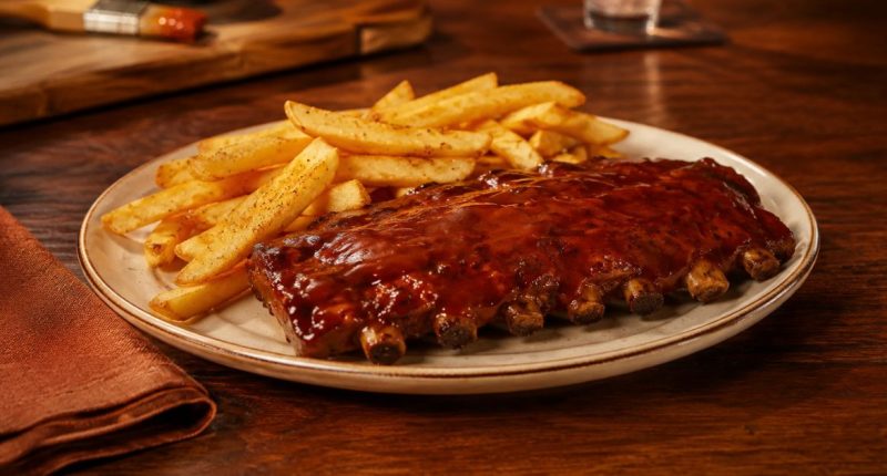 Duas porções de Junior Ribs servidas com acompanhamentos em uma mesa do Outback
