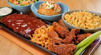Tábua do Outback com costela, massa, carnes e acompanhamentos servida para compartilhar entre amigos ou familiares.