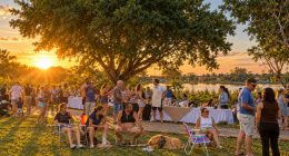 Público na primeira edição da Feira da Lagoa Itatiaia durante o pôr do sol.