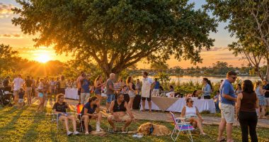 Público na primeira edição da Feira da Lagoa Itatiaia durante o pôr do sol.