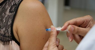 Profissional de saúde aplicando vacina no braço de adolescente em unidade de vacinação.